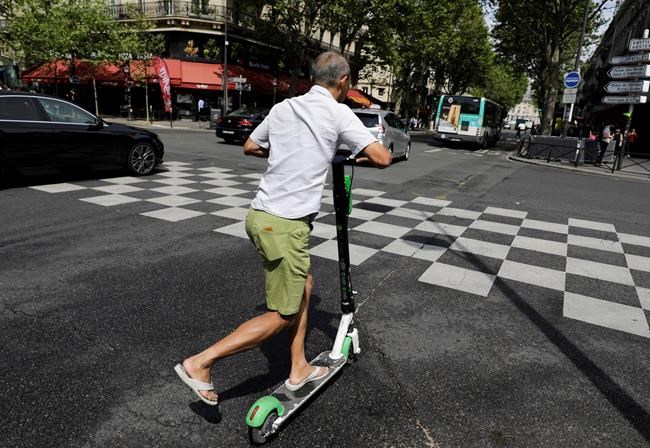 A man rides an electric scooter in Paris, Monday, Aug. 12, 2019. The French government is meeting with people who've been injured by electric scooters as it readies restrictions on vehicles that are transforming the Paris cityscape. The Transport Ministry says Monday's closed-door meeting is part of consultations aimed at limiting scooter speeds and where users can ride and park them. (AP Photo/Lewis Joly)