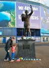 Five year old Grace Elliott and father Chris lay a Southampton FC scarf on the statue of former Cardiff City soccer player Frederick Charles Keenor outside Cardiff City Football Club in Cardiff, Wales, Tuesday Jan. 22, 2019 after a plane with new signing Emiliano Sala on board went missing over the English Channel. The French civil aviation authority said Tuesday Jan. 22, 2019, Argentine soccer player Emiliano Sala was aboard a small passenger plane that went missing off the coast of the island of Guernsey. French and British maritime authorities are searching the English Channel for the plane. (Ben Birchall/PA via AP)