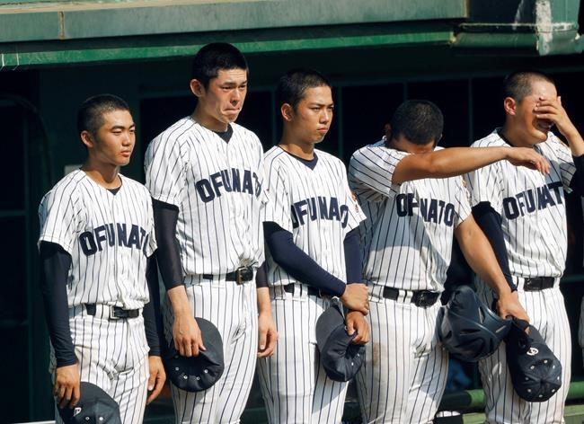 In this July 25, 2019, photo, Ofunato High School pitcher Roki Sasaki, second from left, and teammates cry after they lost to Hanamaki Higashi High School 12-2 in their final baseball game at the Iwate Prefecture qualifier in Morioka, northern Japan. A decision by the high school's manager Yohei Kokubo not to use his star pitcher Sasaki in the final for the prestigious national tournament has the Japanese sporting fraternity up in arms. The gamble ended in defeat, and Ofunato was inundated with phone calls from people demanding an explanation. It sparked harsh criticism of the coach but also a wider debate about the popular tournament’s win-at-all-costs approach, with even Chicago Cubs pitcher Yu Darvish weighing in. (Kyodo News via AP)