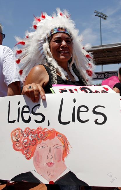 A demonstrator holds a sign to protest the visit of President Donald Trump to the border city after the Aug. 3 mass shooting in El Paso, Texas, Wednesday, Aug. 7, 2019. Aiming to play the traditional role of healer during national tragedy, President Donald Trump paid visits Wednesday to cities reeling from the mass shootings. (AP Photo/Andres Leighton)