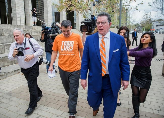 Texas men's tennis coach Michael Center, center left, walks with Defense lawyer Dan Cogdell, center right, away from the United States Federal Courthouse in Austin, Texas, Tuesday, March 12, 2019. Center is among a few people in the state charged in a scheme that involved wealthy parents bribing college coaches and others to gain admissions for their children at top schools, federal prosecutors said Tuesday. (Ricardo B. Brazziell