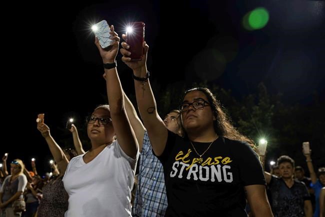 Karina Cardoso and Linda Nevarez hold their cellphone flashlights up during a vigil Sunday, Aug. 4, 2019, at Ponder Park in honor to the victims of a mass shooting occurred in Walmart on Saturday, Aug. 3, 2019, in El Paso, Texas. (Lola Gomez/Austin American-Statesman via AP)