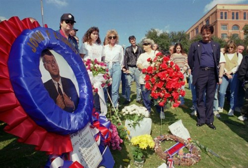 FILE - In this Nov. 22, 1995, file photo, people pause during a moment of silence at Dealey Plaza in Dallas, where President John F. Kennedy was assassinated. Loose gatherings of the curious and conspiracy-minded have marked past anniversaries of the assassination of President Kennedy. But in the place where the president's motorcade passed through and shots rang out on Nov. 22, 1963, a solemn ceremony on the 50th anniversary of his death is designed to avoid such distractions, with brief remarks by the mayor and the tolling of church bells. (AP Photo/Tim Sharp, File)