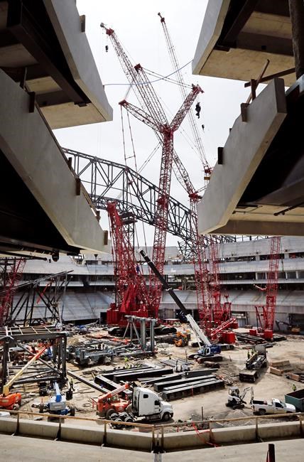 In this Monday, May 6, 2019 photo, the partially erect east roof truss is being installed with a Manitowoc 31000 crane, center, their largest capacity crawler ever designed and built, at the Texas Rangers' Globe Life Field in Arlington, Texas. The truss will support the new Daktronics right field video display measuring 58 by 150 feet. (Tom Fox/The Dallas Morning News via AP)