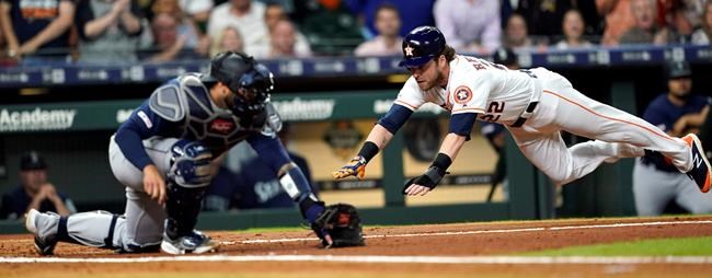 Houston Astros' Josh Reddick (22) dives past Seattle Mariners catcher Omar Narvaez to score during the second inning of a baseball game Saturday, June 29, 2019, in Houston. (AP Photo/David J. Phillip)