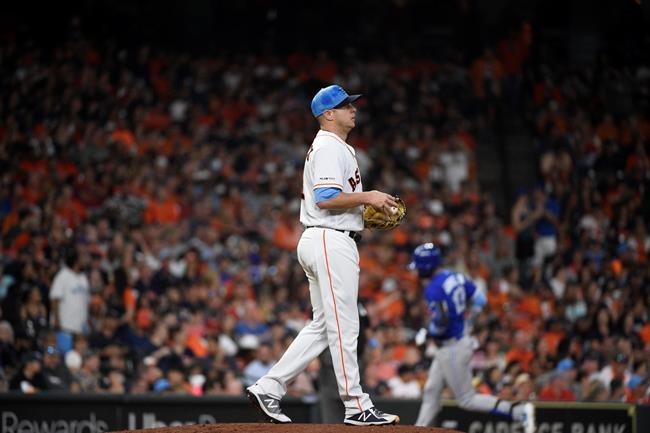 Houston Astros starting pitcher Brad Peacock, left, walks off the mound as Toronto Blue Jays' Lourdes Gurriel Jr., back right, rounds the bases after hitting a two-run home run during the fifth inning of a baseball game, Sunday, June 16, 2019, in Houston. (AP Photo/Eric Christian Smith)