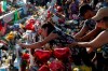 A woman leans over to write a message on a cross at a makeshift memorial at the scene of a mass shooting at a shopping complex, Tuesday, Aug. 6, 2019, in El Paso, Texas. (AP Photo/John Locher)