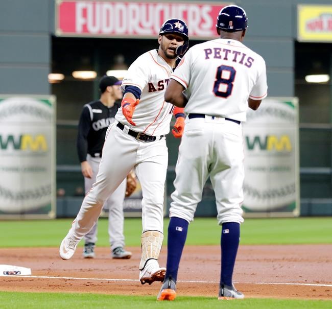 Houston Astros Yuli Gurriel, left, rounds third base and reaches to shake hands with third base coach Gary Pettis (8) after Gurriel's home run during the first inning of a baseball game agains the Colorado Rockies Wednesday, Aug. 7, 2019, in Houston. (AP Photo/Michael Wyke)