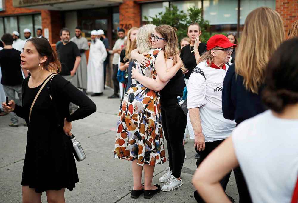 Mark Blinch / The Canadian Press files
People comfort each other following a vigil remembering the victims of a shooting on Danforth Avenue in Toronto in July.