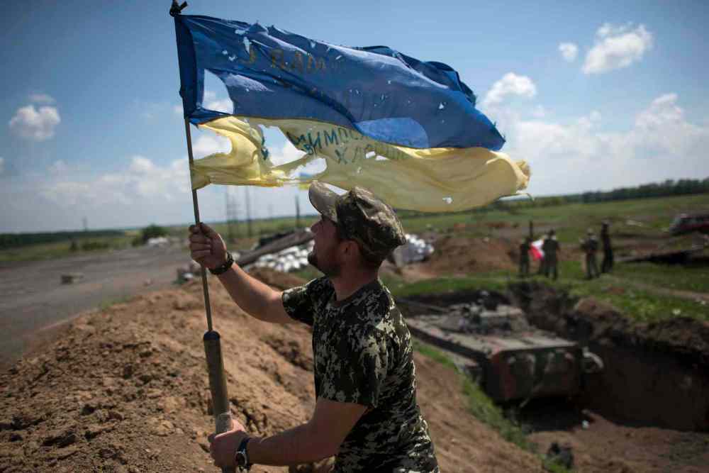 Evgeniy Maloletka / The Associated Press
A Ukrainian soldier puts a Ukrainian flag at the Ukrainian position in Marinka, near Donetsk, eastern Ukraine, Friday. As fears persist that eastern Ukraine is about to fall back into full-scale war, a leader of the international monitoring group is urgently calling for resumed negotiations.
