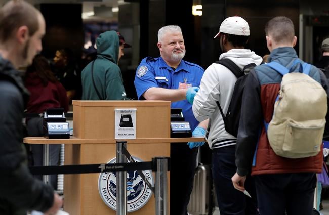 A TSA worker checks hands an identification card back to a traveler, Friday, Jan. 25, 2019, at Seattle-Tacoma International Airport in Seattle. Yielding to mounting pressure and growing disruption, President Donald Trump and congressional leaders on Friday reached a short-term deal to reopen the government for three weeks while negotiations continue over the president's demands for money to build his long-promised wall at the U.S.-Mexico border. (AP Photo/Ted S. Warren)