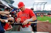 Los Angeles Angels center fielder Mike Trout autographs a bat before the first inning of a baseball game against the Seattle Mariners, Monday, April 1, 2019, in Seattle. (AP Photo/Ted S. Warren)