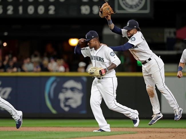 Seattle Mariners' J.P. Crawford, right, playfully taps Tim Beckham, left, with his glove as the Mariners celebrate their 10-2 win over the Detroit Tigers in a baseball game, Thursday, July 25, 2019, in Seattle. Beckham hit a grand slam in the game. (AP Photo/Ted S. Warren)