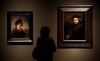FILE - In this file photo dated Thursday, Feb. 16, 2012, a visitor views two self portraits by 17th century Dutch master Rembrandt at the Cleveland Museum of Art's 'Rembrandt in America' exhibition in Cleveland, USA. It is announced Monday April 8, 2019, Dutch soccer teams will be playing with the official soccer ball inscribed with Rembrandt's face and extracts from his work in the Dutch soccer league next season, marking the 350th anniversary of his death.(AP Photo/Amy Sancetta, FILE)