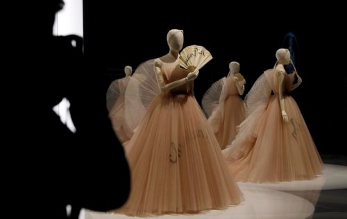 A Christian Dior design by Maria Grazia Chiuri Haute couture Spring/Summer 2018, silk and and embroidery Calico hairstyle created by Stephen Jones, Fan Christian Dior by Eventails Gane 1950-5 paper and wood, on display during a press preview of the largest exhibition in the United Kingdom of the Paris based fashion House of Dior at the V&A Museum in London, Wednesday, Jan. 30, 2019. Billed as the largest and most comprehensive exhibition ever staged in Britain on the revered fashion house, the exhibition traces the impact of Dior over seven decades and showcases dozens of spectacular couture gowns. (AP Photo/Alastair Grant)