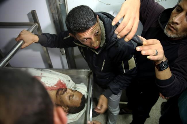 EDS NOTE: GRAPHIC CONTENT - Mourners gather over the body of Hamas militant of Alla Boubali, who was killed during an Israeli airstrike at Hamas militants post central Gaza Strip, at the morgue of Al-Aqsa hospital in Deir el-Balah, central Gaza Strip, Friday, May 3, 2019. Three Palestinians, including two militants, were killed by Israeli fire Friday after gunshots from the Gaza Strip wounded two Israeli soldiers, officials said. (AP Photo/Adel Hana)