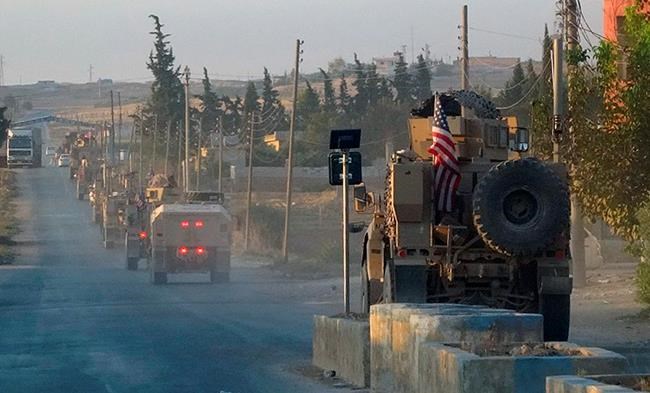 In this image provided by Hawar News Agency, ANHA, U.S. military vehicles travel down a main road in northeast Syria, Monday, Oct. 7, 2019. U.S.-backed Kurdish-led forces in Syria said American troops began withdrawing Monday from their positions along Turkey's border in northeastern Syria, ahead of an anticipated Turkish invasion that the Kurds say will overturn five years of achievements in the battle against the Islamic State group. (ANHA via AP)