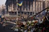 A woman walks past a barricade covered in flowers left to those killed in recent clashes in Kiev's Independence Square, Ukraine, Friday, March 7, 2014. In the background is the Trade Unions Building, which was damaged in a fire in late February. (AP Photo/David Azia)
