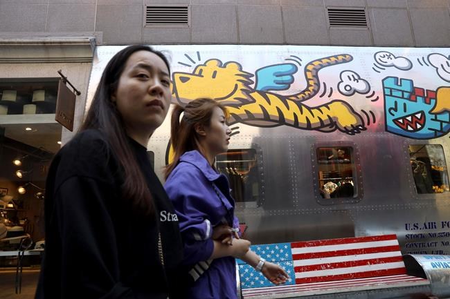 Consumers past by a U.S. fashion apparel store in Beijing Monday, May 6, 2019. U.S. President Donald Trump raised pressure on China on Sunday, threatening to hike tariffs on $200 billion worth of Chinese goods in a tweet that sent financial markets swooning. Trump's comments, delivered on Twitter, came as a Chinese delegation was scheduled to resume talks in Washington on Wednesday aimed at resolving a trade war that has shaken investors and cast gloom over the world economy. (AP Photo/Ng Han Guan)