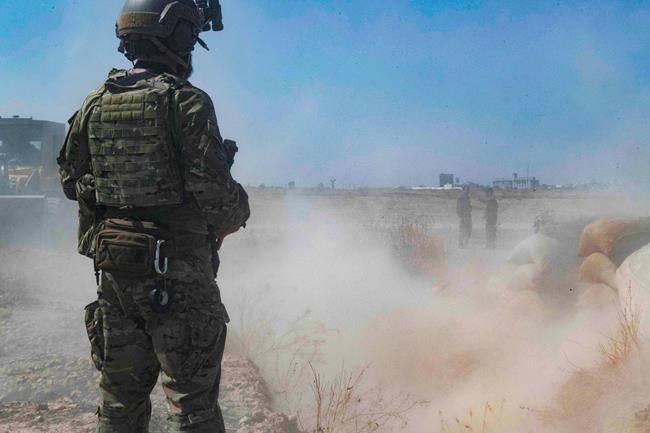 In this Sept. 21, 2019, photo, released by the U.S. Army, a U.S. soldier oversees members of the Syrian Democratic Forces as they demolish a Kurdish fighters' fortification as part of the so-called