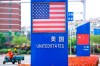 In this Wednesday, May 8, 2019, photo, a worker drives an electric cart past a display featuring the U.S. and Chinese flags in a special trade zone in Qingdao in eastern China's Shandong province. China said Thursday it will retaliate if President Donald Trump goes ahead with more tariff hikes in a fight over technology and trade, ratcheting up tensions ahead of negotiations in Washington. (Chinatopix via AP)