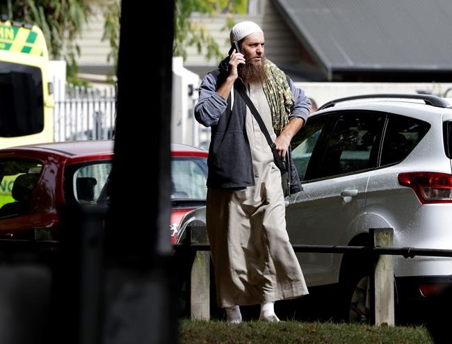A man talks on his mobile phone across the road from a mosque in central Christchurch, New Zealand, Friday, March 15, 2019. A witness says a number of people have been killed in a mass shooting at a mosque in the New Zealand city of Christchurch; police urge people to stay indoors. (AP Photo/Mark Baker)