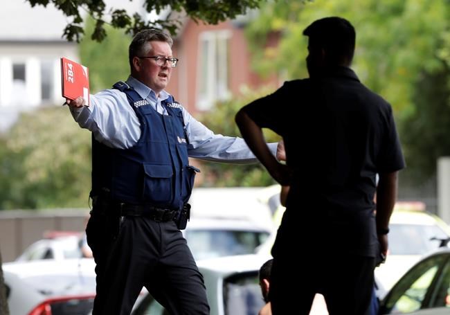 A police officer attempts to move people away from across the road from a mosque in central Christchurch, New Zealand, Friday, March 15, 2019. A witness says a number of people have been killed in a mass shooting at a mosque in the New Zealand city of Christchurch. Police urge people to stay indoors.(AP Photo/Mark Baker)