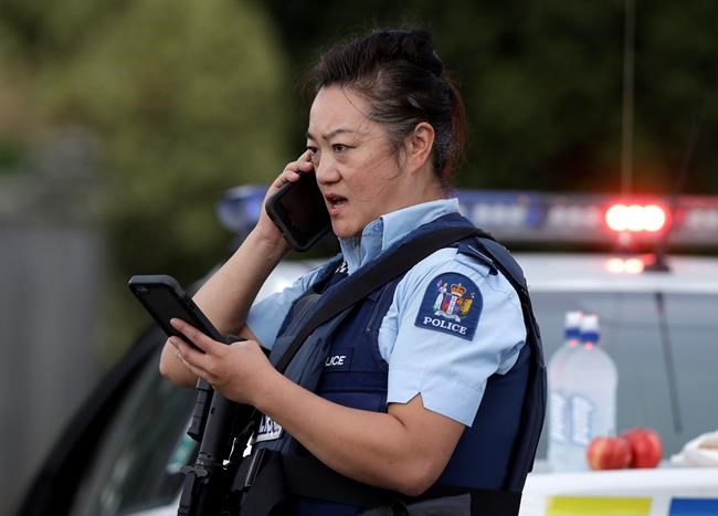 A police officer talks on her phone as a roadblock near a mass shooting at a mosque in Linwood, Christchurch, New Zealand, Friday, March 15, 2019. Multiple people were killed during shootings at two mosques full of people attending Friday prayers. (AP Photo/Mark Baker)