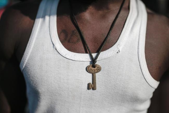 A sub-Saharan poses with a key necklace at Ouled Ziane camp in Casablanca, Morocco, Thursday, Dec. 6, 2018. As Morocco prepares to host the signing of a landmark global migration agreement next week, hundreds of migrants are languishing in a Casablanca camp rife with hunger, misery and unsanitary conditions. These sub-Saharan Africans who dream of going to Europe are a symbol of the problems world dignitaries are trying to address with the U.N.'s first migration compact. (AP Photo/Mosa'ab Elshamy)