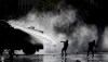 Demonstrators clash with a police water cannon during an anti-government protest in Santiago, Tuesday, Nov. 5, 2019. Chileans have been taking to the streets and clashing with the police to demand better social services and an end to economic inequality, even as the government announced that weeks of demonstrations are hurting the country's economic growth. (AP Photo/Esteban Felix)