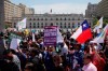 Anti-government demonstrators march past La Moneda presidential palace in Santiago, Chile, Wednesday, Oct. 30, 2019. President Sebastian Pinera cancelled two major international summits after nearly two weeks of nationwide protests over economic inequality that have left at least 20 dead and damaged businesses and infrastructure around the country. (AP Photo/Rodrigo Abd)