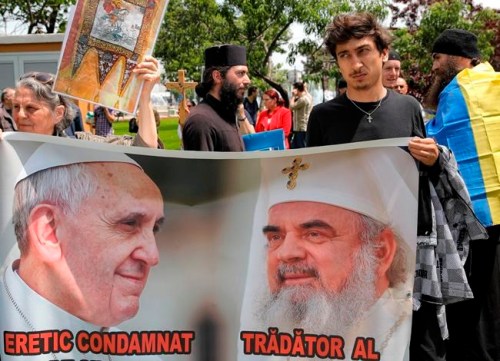 People hold a banner depicting Pope Francis, left, and the head of Romania's Orthodox church, Patriarch Daniel during a protest by dozens of Orthodox worshipers against the upcoming visit of Pope Francis in Bucharest, Romania, Saturday, May 25, 2019. The Roman Catholic pontiff will arrive in Romania at the end of May, 20 years after Pope John Paul II visited the former communist country. (AP Photo/Vadim Ghirda)