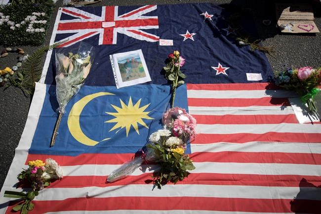 Flowers, messages and flags of New Zealand and Malaysia are seen at the memorial site for the victims of Friday's shooting, outside the Al Noor mosque in Christchurch, New Zealand, Tuesday, March 19, 2019. Christchurch was beginning to return to a semblance of normalcy Tuesday. Streets near the hospital that had been closed for four days reopened to traffic as relatives and friends of Friday's shooting victims continued to stream in from around the world. (AP Photo/Vincent Thian)