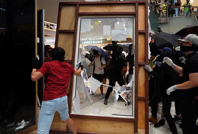 Protesters damage an advertisement board in Hong Kong on Sunday, Sept. 22, 2019. Protesters in Hong Kong trampled a Chinese flag, vandalized a subway station and lit a fire across a wide street on Sunday, as pro-democracy demonstrations took a violent turn once again. (AP Photo/Vincent Yu)