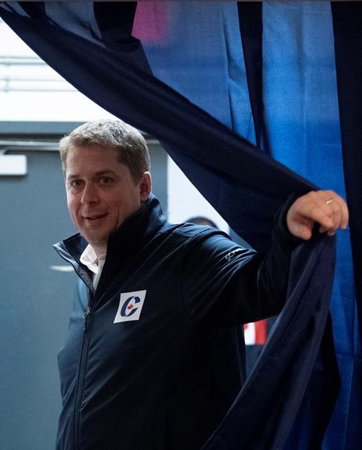 Conservative leader Andrew Scheer pulls back a curtain as he arrives at a campaign office in Vancouver, Sunday October 20, 2019. THE CANADIAN PRESS/Adrian Wyld
