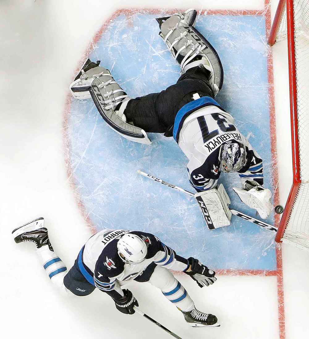 Winnipeg Jets goalie Connor Hellebuyck (37) and defenseman Ben Chiarot (7) reach for the puck on a shot that missed the net during the third period in Game 5 of an NHL hockey second-round playoff series against the Nashville Predators Saturday, May 5, 2018, in Nashville, Tenn. The Jets won 6-2 to take a 3-2 lead. (AP Photo/Mark Humphrey)