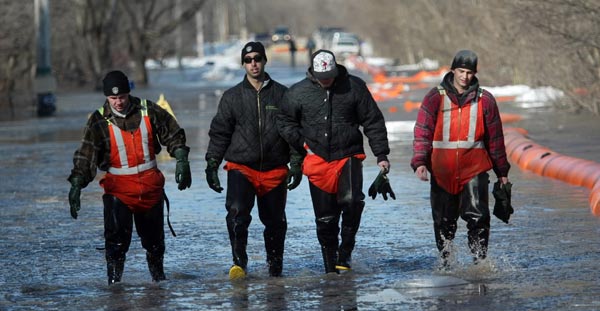 Phil Hossack / Winnipeg Free Press
A city crew wades out of Christie road where a “Tiger” tube dike was overwhelmed in a low section of the road. Homes were not affected, and flooding was localized.