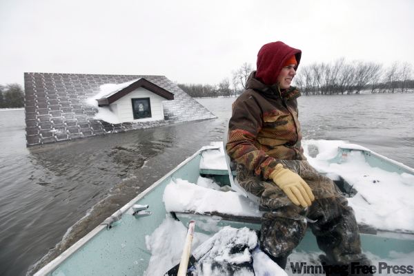 Richard Tsong-Taatarii / The Associated Press
Doug Stensgaard uses one of his family's boats to get back to their home from the Red River near Fargo on Wednesday.