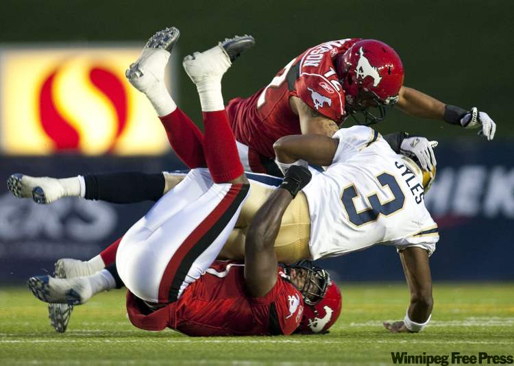 Jeff McIntosh / THE CANADIAN PRESS
Winnipeg Blue Bombers quarterback Steven Jyles, centre, gets sacked by Calgary Stampeders Juwan Simspon, top, and Malik Jackson during third quarter CFL football action in Calgary, Saturday.