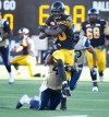 CP
Hamilton Tiger-Cats' Terrence Toliver, centre, gets some yards while being tackled by Winnipeg Blue Bombers' Khalil Bass, bottom, during the second half of CFL football action in Hamilton, Ont., on Sunday. (Peter Power / The Canadian Press)