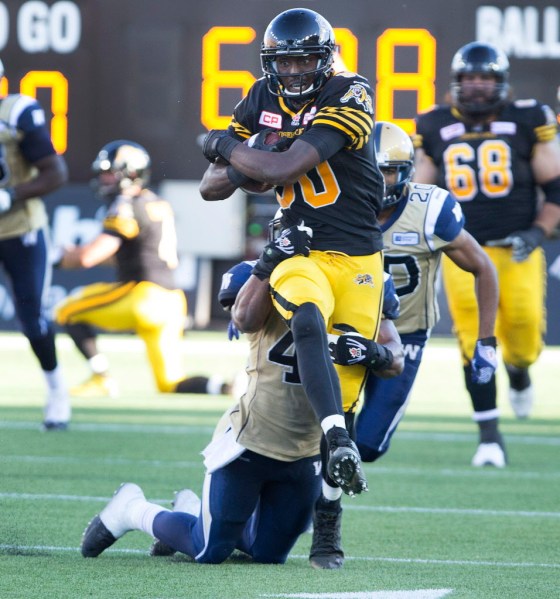 CPHamilton Tiger-Cats' Terrence Toliver, centre, gets some yards while being tackled by Winnipeg Blue Bombers' Khalil Bass, bottom, during the second half of CFL football action in Hamilton, Ont., on Sunday. (Peter Power / The Canadian Press)