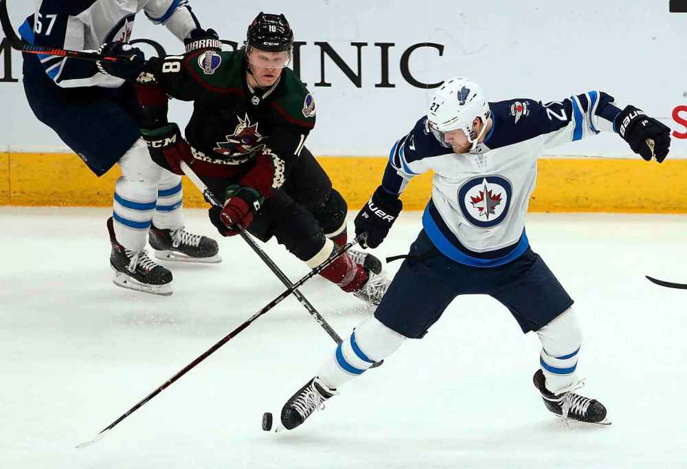 Winnipeg Jets left wing Nikolaj Ehlers (27) kicks the puck as Arizona Coyotes center Christian Dvorak (18) closes in during the second period of an NHL hockey game Saturday, April 6, 2019, in Glendale, Ariz. (AP Photo/Ross D. Franklin)