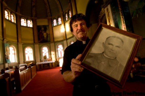 PHIL.HOSSACK@FREEPRESS.MB.CA
Father Taras Kowch with a portrait of his heroic grandfather, Father Emilian Kowcz.