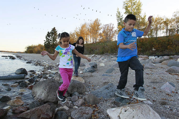 John Woods / Winnipeg Free Press
Anika Wetherill (centre), Kenisty St Clair (background) and Zach Cruly from Little Saskatchewan First Nation play on the shore of Lake Winnipeg at Misty Lake Lodge in Gimlie. The community has been evacuated due to flooding since May of 2011.