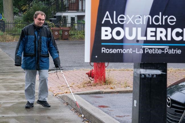 Jerome Plante, who is visually impaired, walks along a sidewalk towards a low-hanging election sign in Montreal on Tuesday, October 1, 2019. An advocacy group for the visually impaired is calling out political parties for their low-hanging Montreal election signs that create a hazard for those unable to see them. THE CANADIAN PRESS/Paul Chiasson