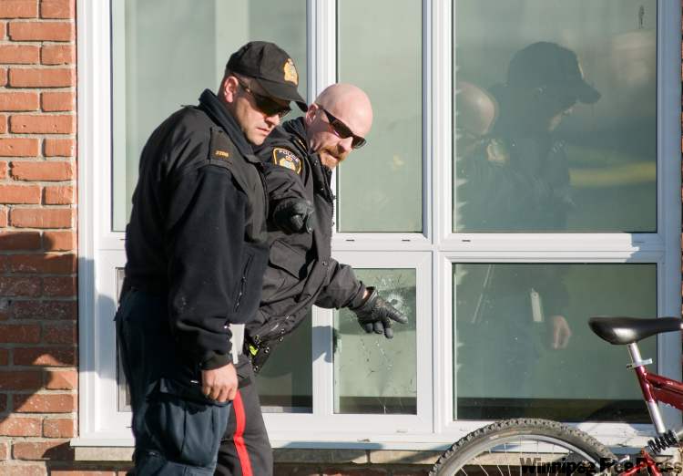 DAVID LIPNOWSKI / winnipeg free press
Police investigate a gunshot hole in a window of a suite in the 200 block of Stella Walk Sunday morning.