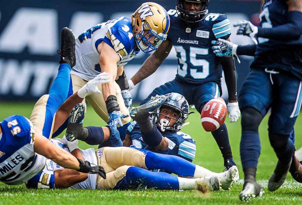 Toronto Argonauts' Martese Jackson fumbles the ball as Winnipeg Blue Bombers' Jesse Briggs, top, looks on during the first half of CFL football action in Toronto, Saturday July 21, 2018.