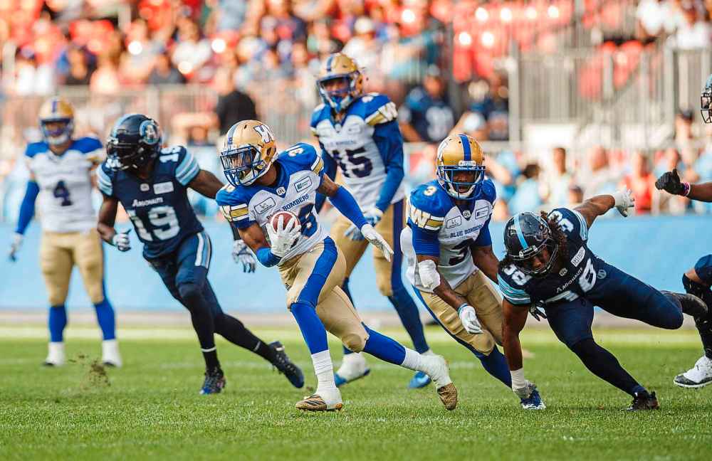 Winnipeg Blue Bombers' Marcus Sayles runs after getting an interception with teammate Kevin Fogg, centre, past Toronto Argonauts' Declan Cross during second half CFL football action in Toronto on Saturday, July 21, 2018.