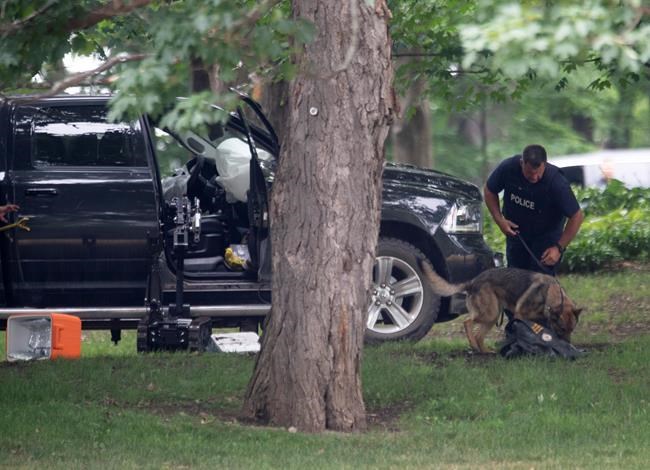 An RCMP officer works with a police dog as they move through the contents of a pick up truck on the grounds of Rideau Hall in Ottawa, Thursday July 2, 2020. THE CANADIAN PRESS/Adrian Wyld