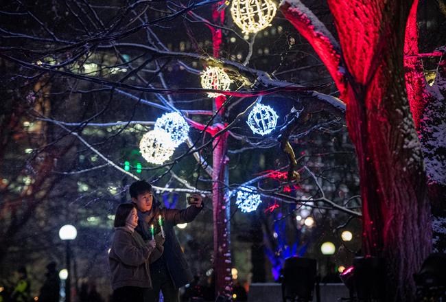 People take a photo together during the opening night of Christmas Lights Across Canada, in Ottawa, on Wednesday, Dec. 4, 2019. The likelihood that most Canadians will enjoy a holly jolly Christmas season of gatherings, caroling and travel is unlikely, say public health experts who encourage those who revel in holiday traditions to accept more sacrifices ahead. THE CANADIAN PRESS/Justin Tang